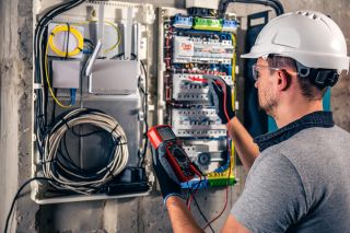 Elektriker prüft Sicherungskasten vor Renovierung