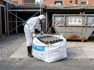 Handwerker in Schutzausrüstung verpackt Eternitplatten in Asbest-BigBags