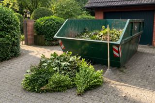 Container mit Grünschnitt in der Garageneinfahrt